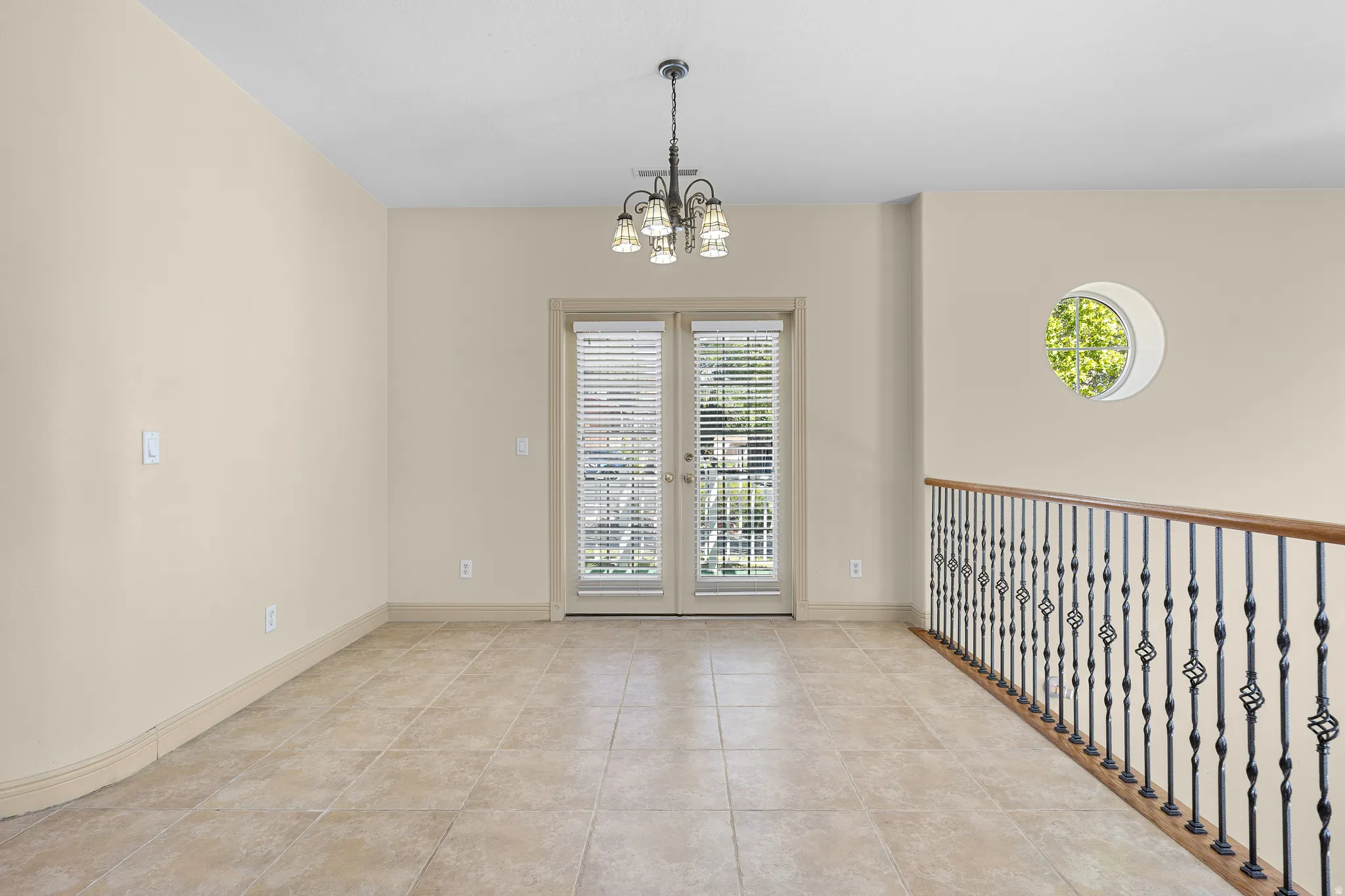 Unfurnished room featuring suspended lighting, light tile patterned floors, and french doors