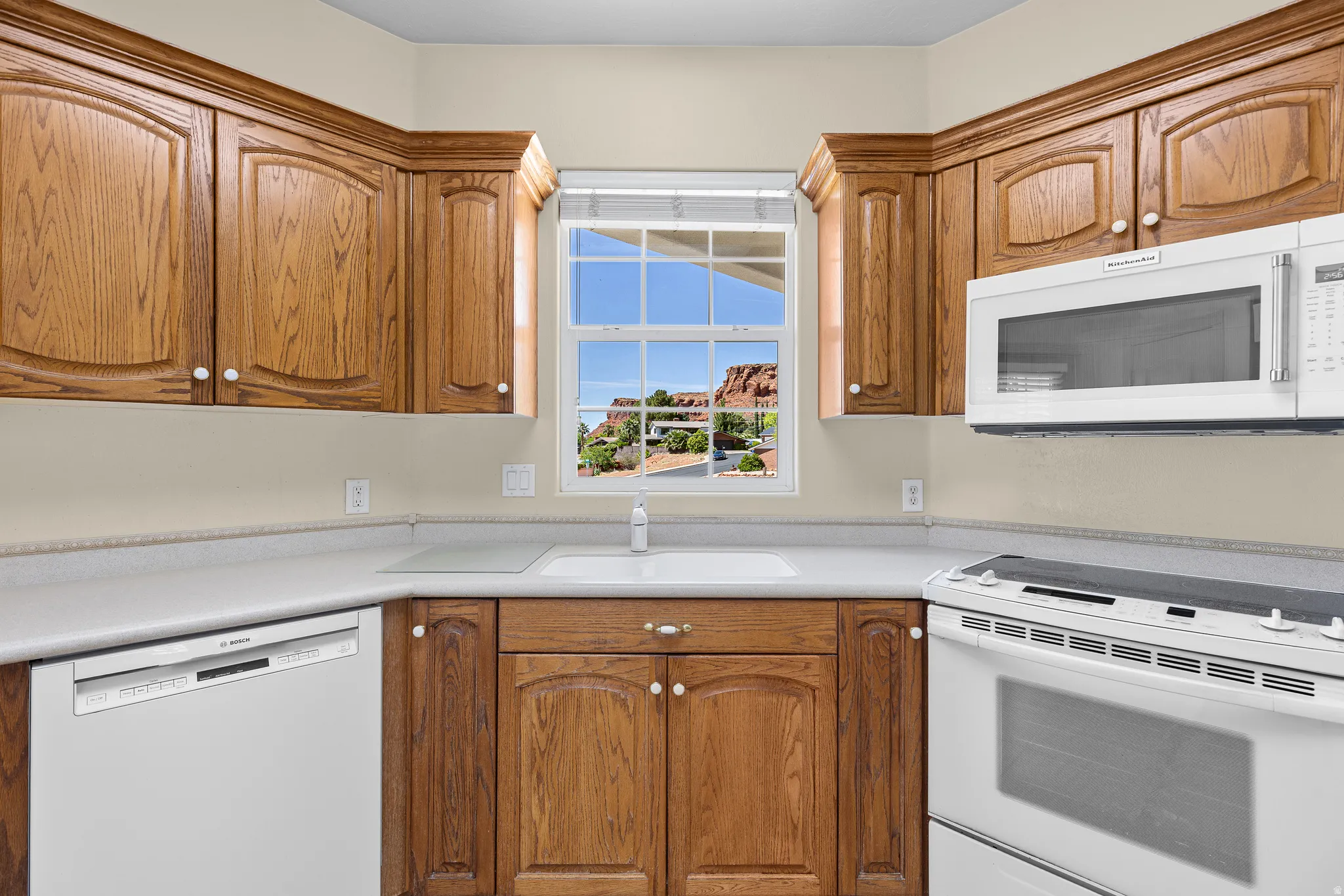 Kitchen with white appliances, wood finish cabinets, and light countertops