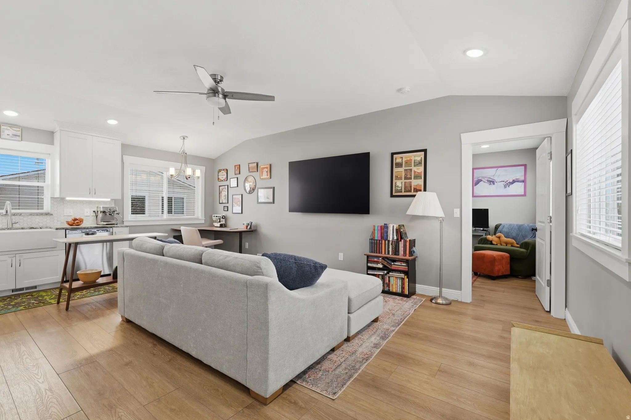 ADU living room featuring lofted ceiling, healthy amount of natural light, hanging lights, ceiling fan, and light wood finished floors