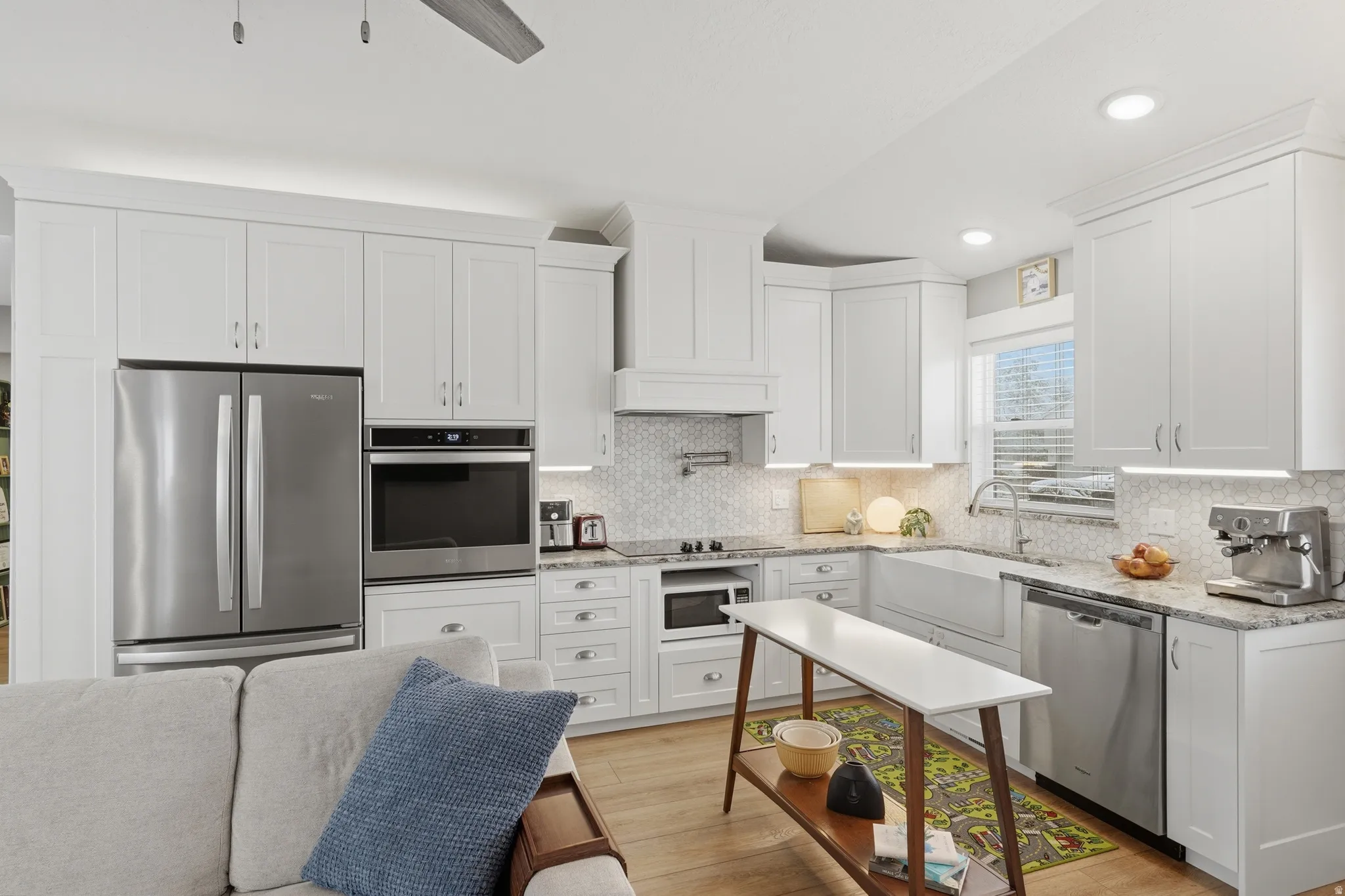 ADU Kitchen with stainless steel appliances, white cabinets, light stone counters, light wood finished floors, and recessed lighting