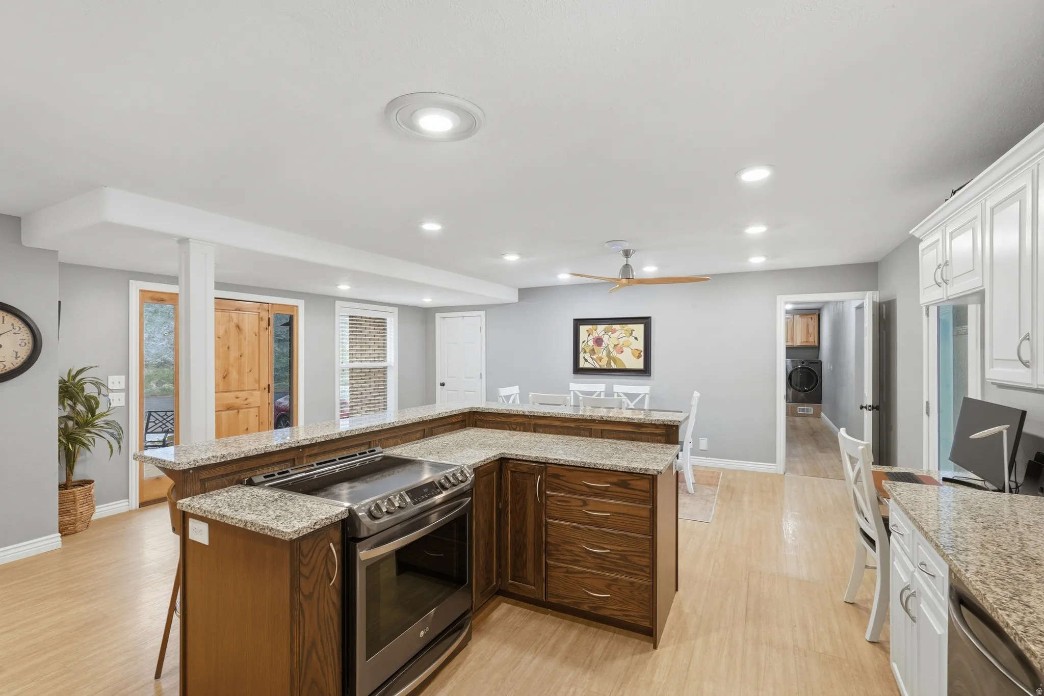 Kitchen featuring granite counters, stainless steel appliances, a kitchen breakfast bar, light wood-style flooring, and recessed lighting