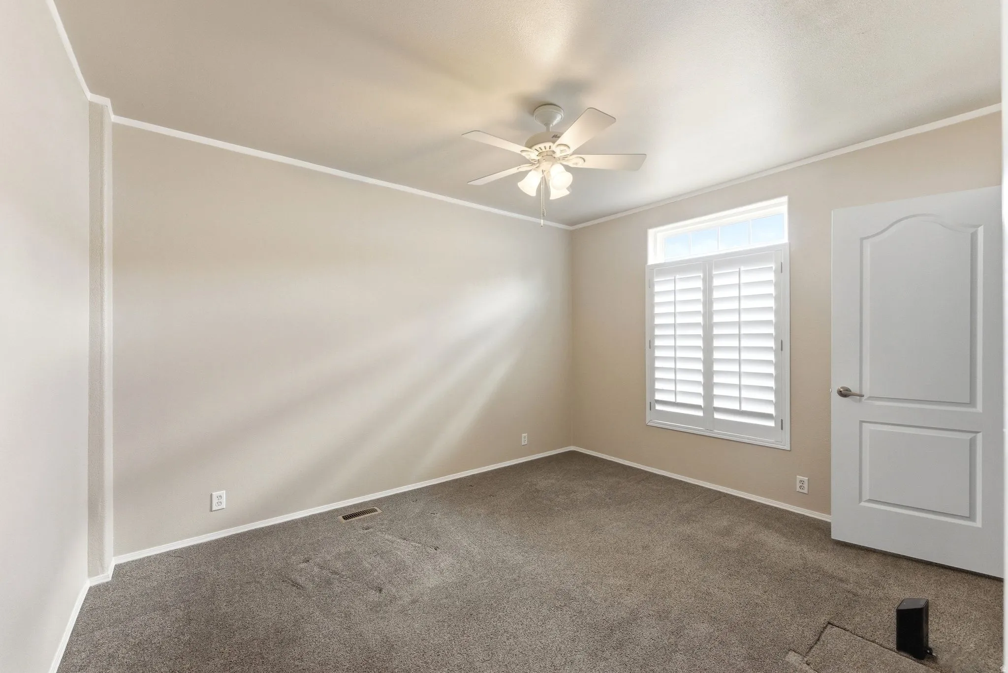 Spare room with dark colored carpet, ornamental molding, and ceiling fan
