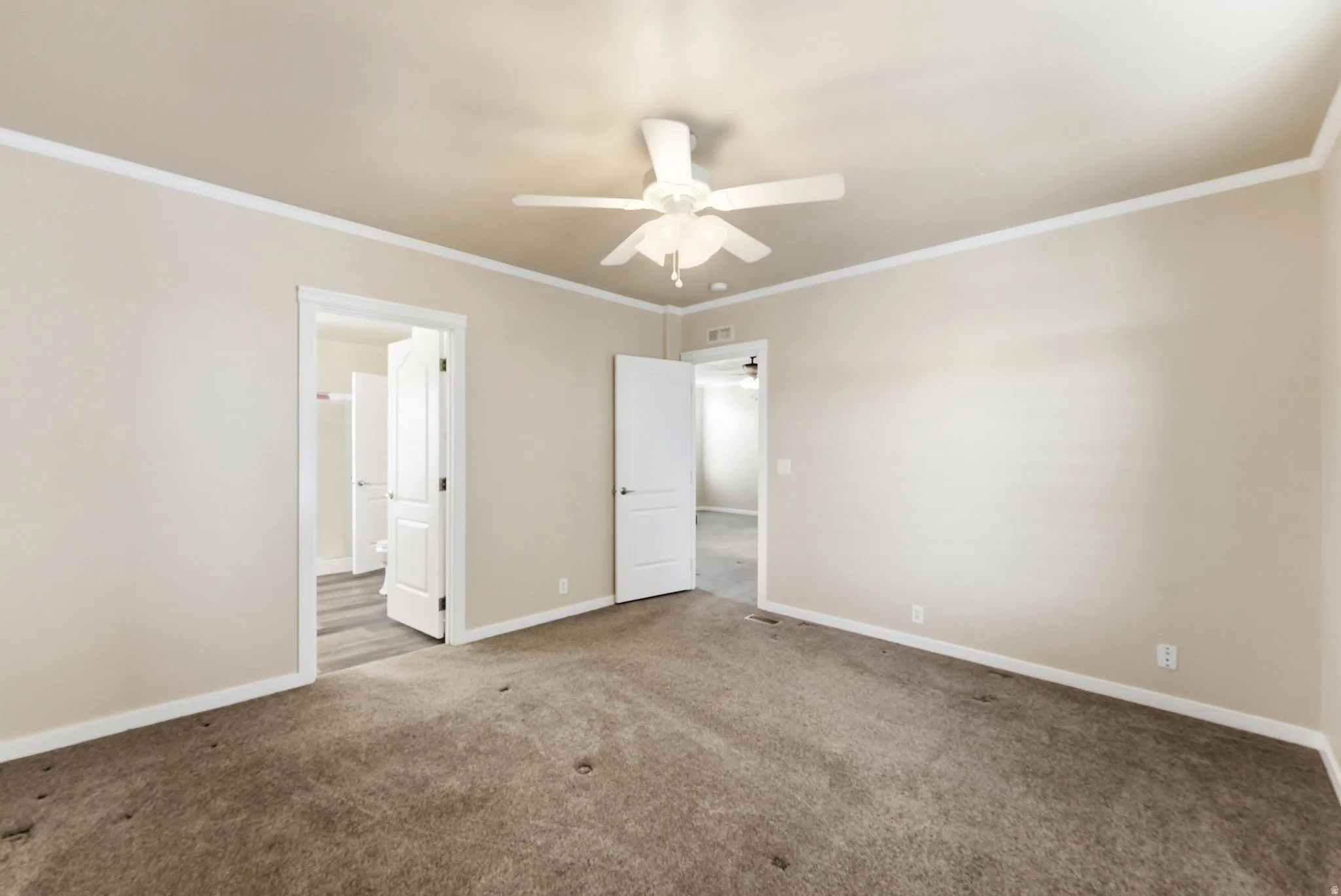 Unfurnished bedroom with carpet floors, ceiling fan, and crown molding