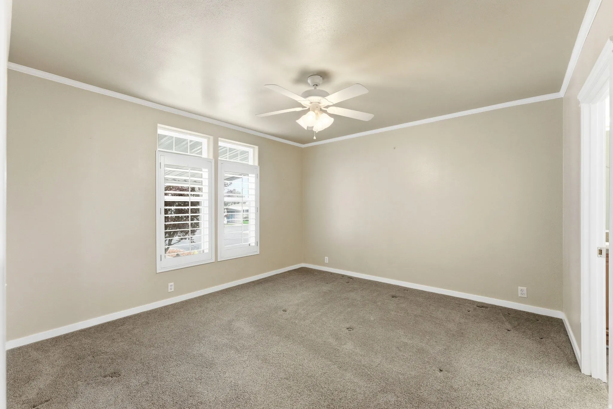 Carpeted empty room featuring ornamental molding and ceiling fan