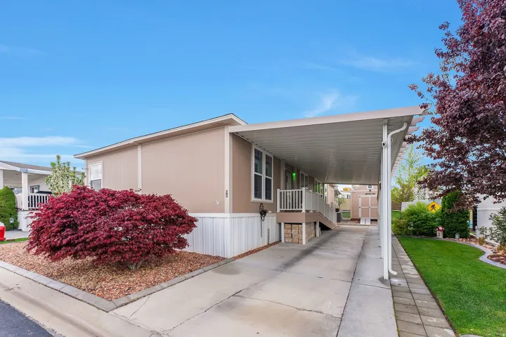View of side of home featuring covered porch, a carport, driveway, and a storage unit