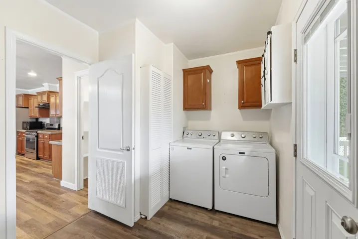 Laundry room with ornamental molding, dark wood-style floors, cabinet space, and washer and clothes dryer