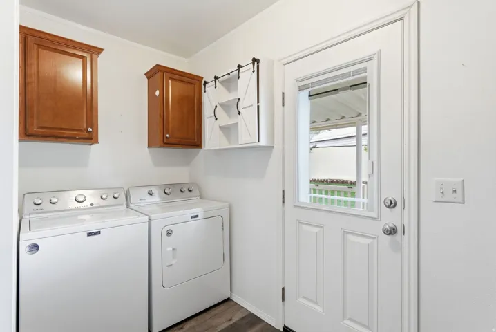 Laundry room with washing machine and clothes dryer, dark wood-type flooring, cabinet space, and ornamental molding