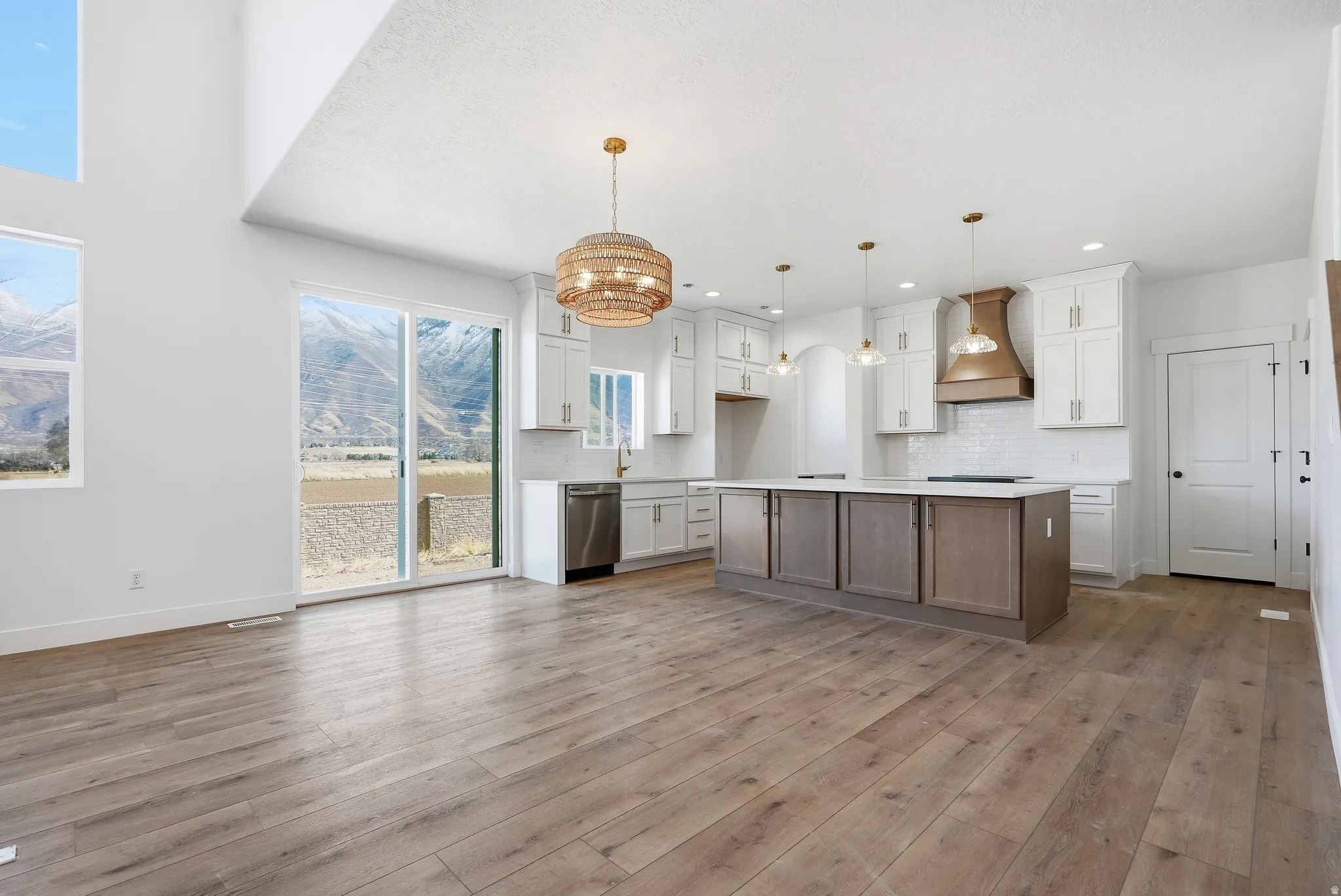 Two tone kitchen featuring dual tone cabinets, a kitchen island, light countertops, decorative backsplash, and open floor plan