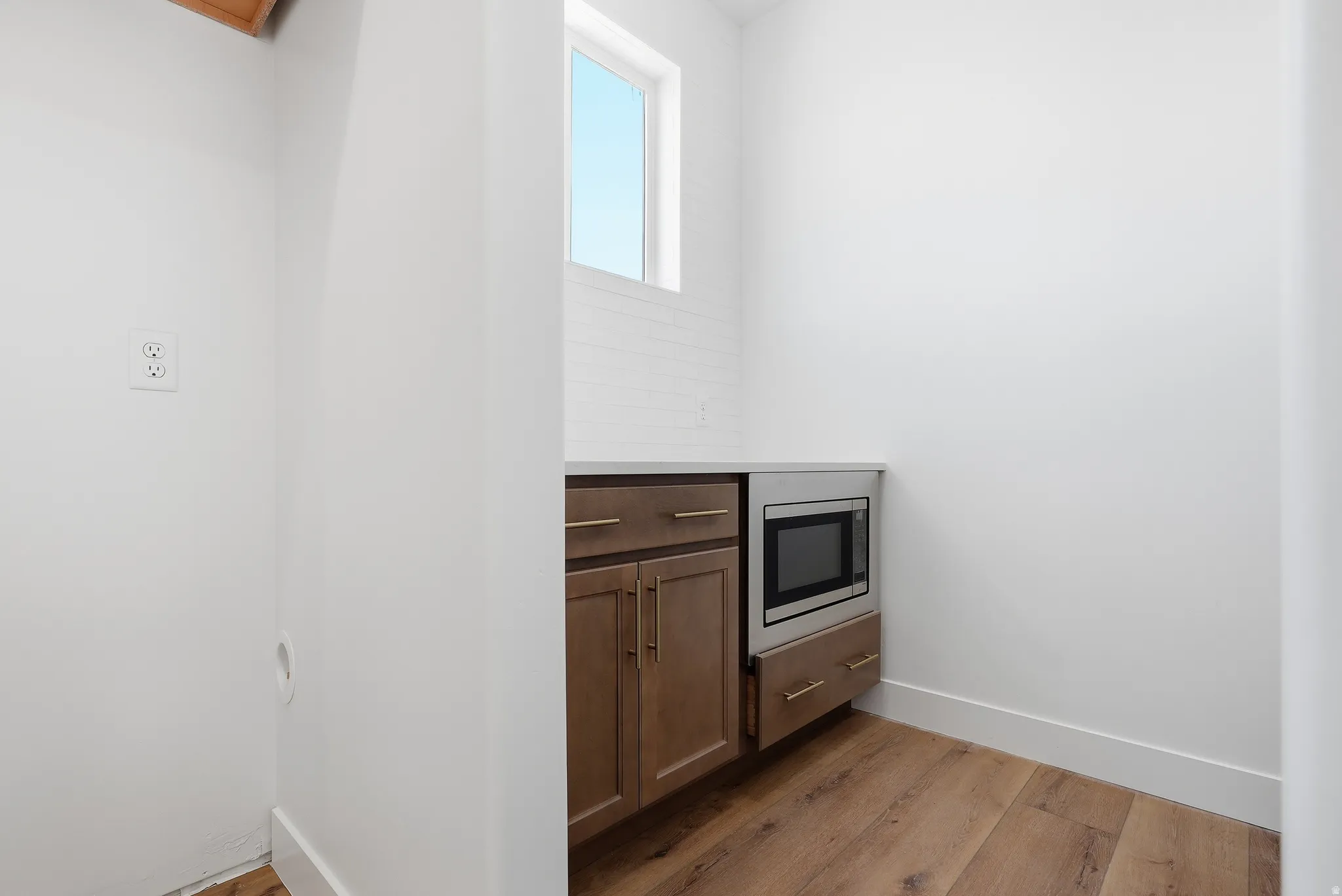 Kitchen with dark wood-style floors, light stone counters, wood finish cabinets, and stainless steel microwave