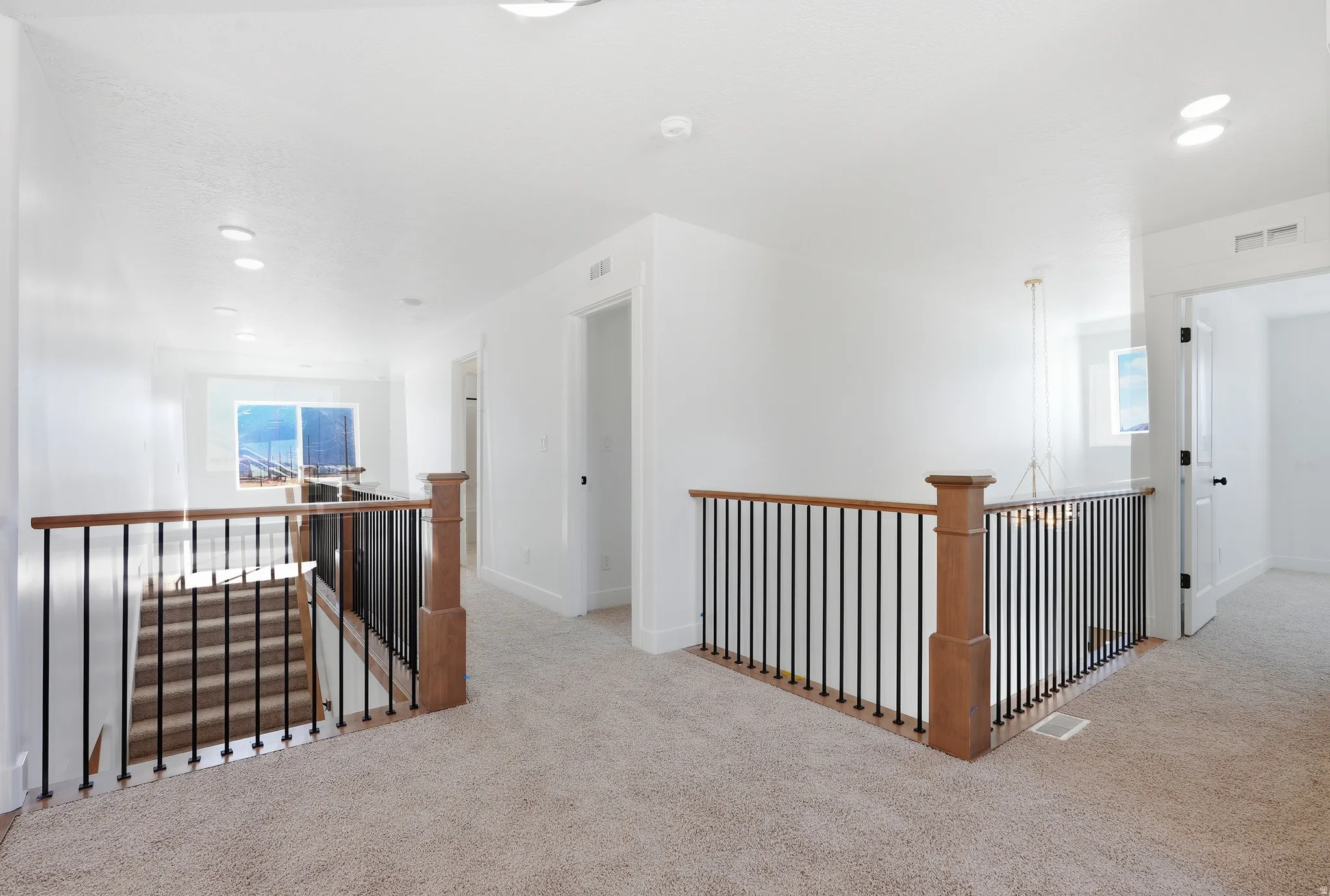 Hallway with an upstairs landing, carpet floors, and recessed lighting