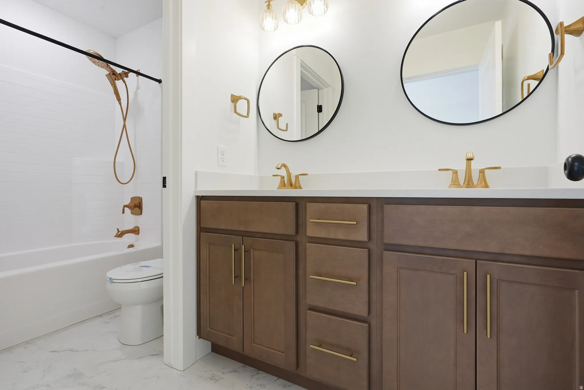 Full bath with double vanity, shower / washtub combination, and light marble finish flooring