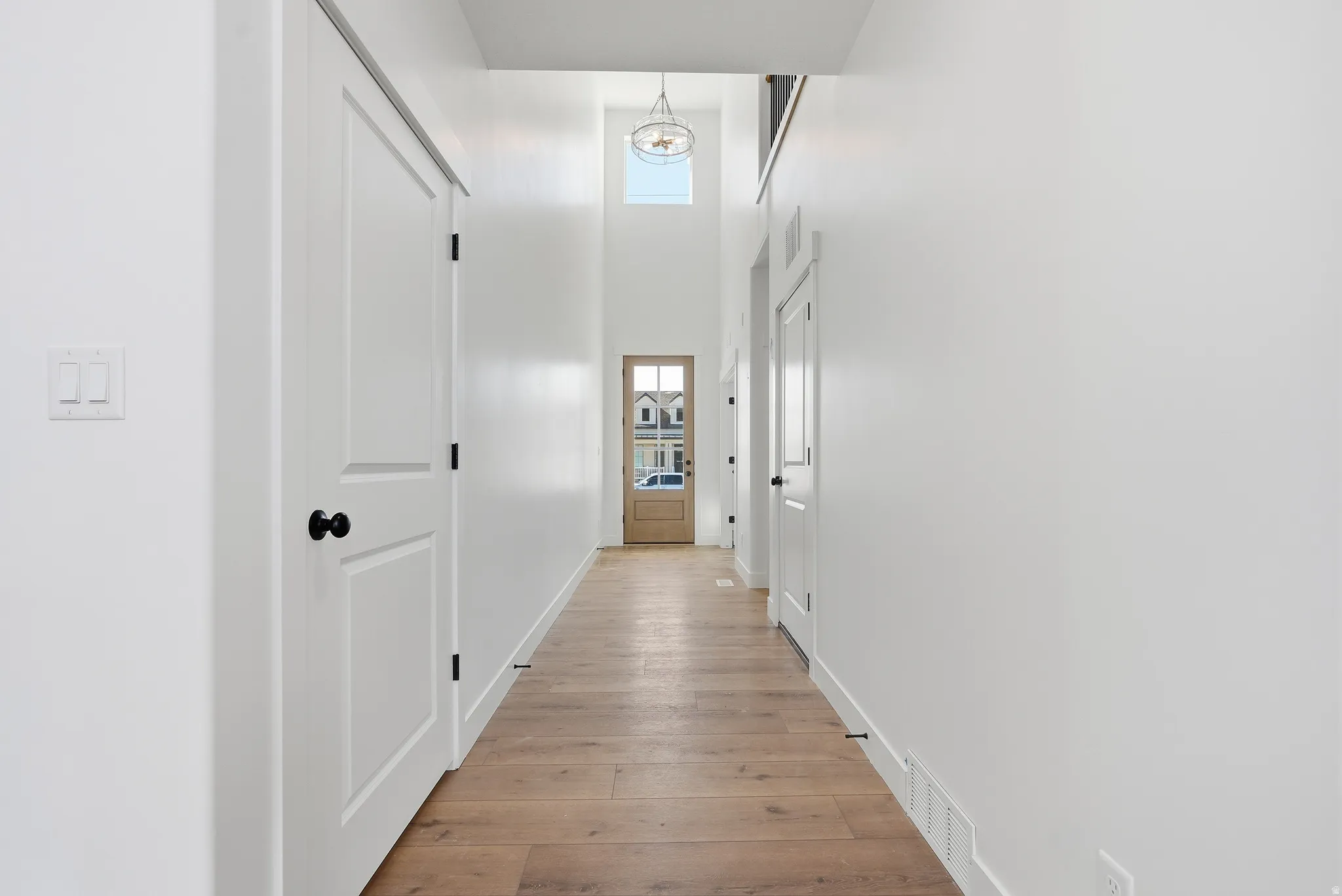 Hallway featuring a high ceiling and light wood-type flooring