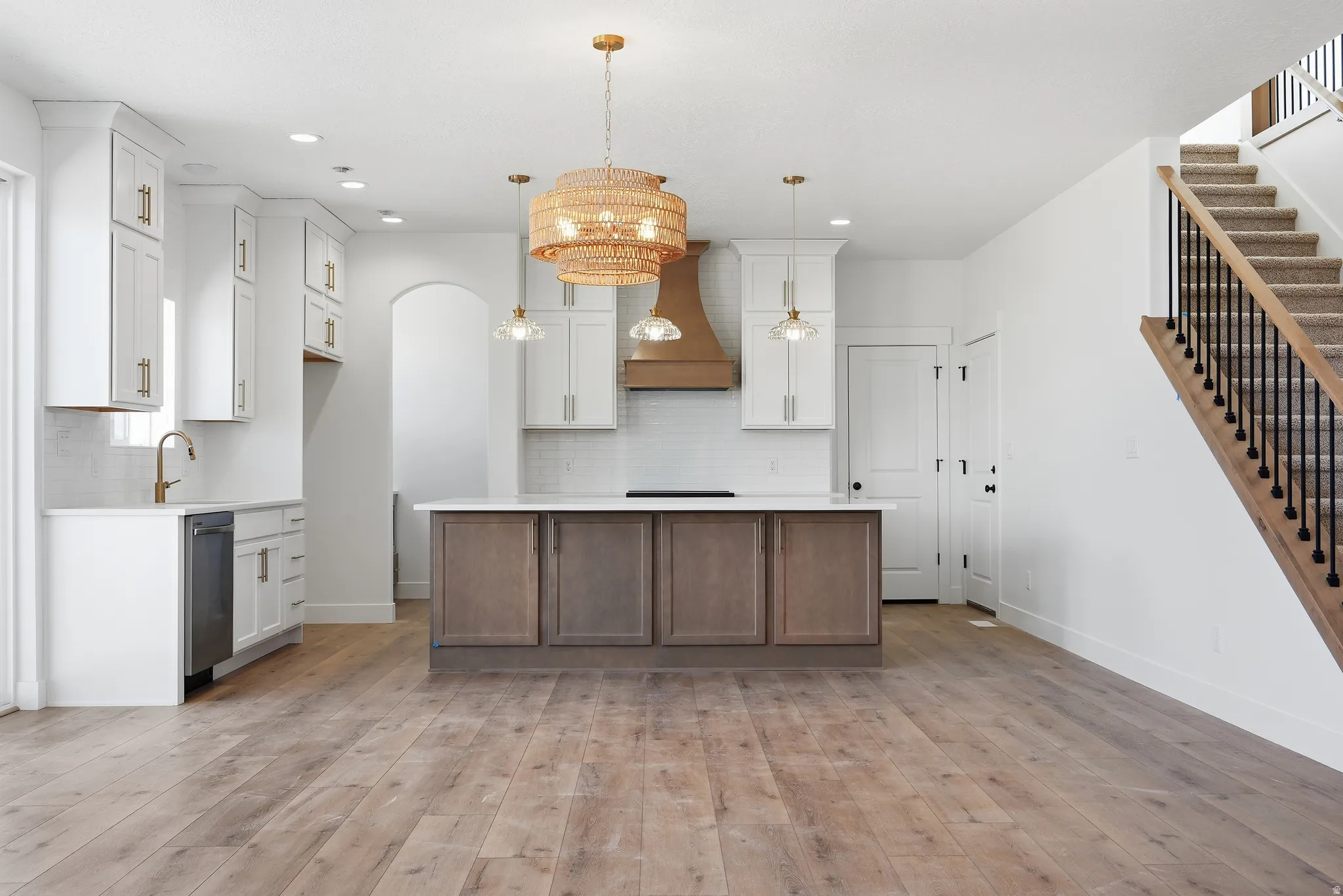 Dual tone kitchen featuring two tone cabinets, a kitchen island, light wood-style flooring, backsplash, and stainless steel dishwasher