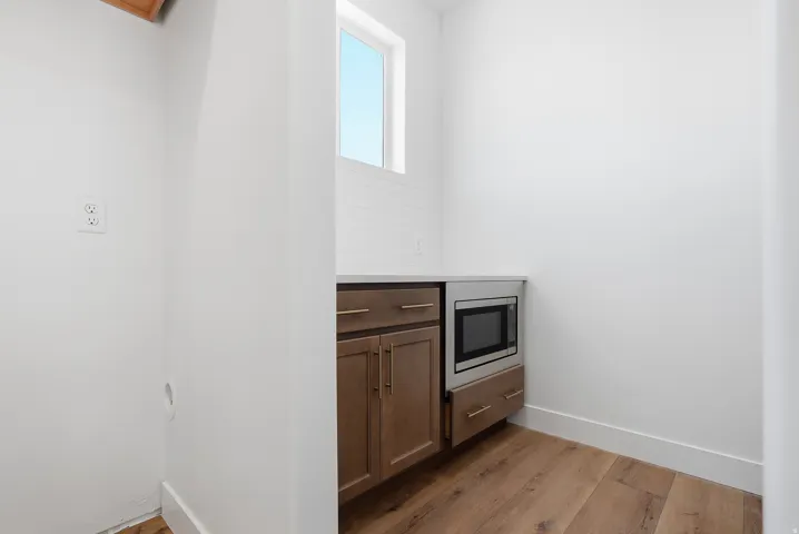 Kitchen with dark wood-style floors, light stone counters, wood finish cabinets, and stainless steel microwave
