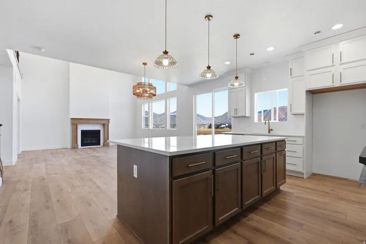 Kitchen with two tone cabinetry, light wood-style floors, a kitchen island, a fireplace, and backsplash