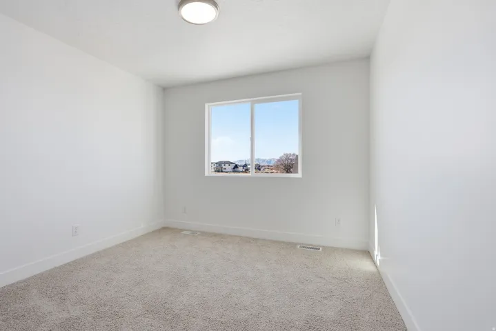 Carpeted spare room featuring baseboards