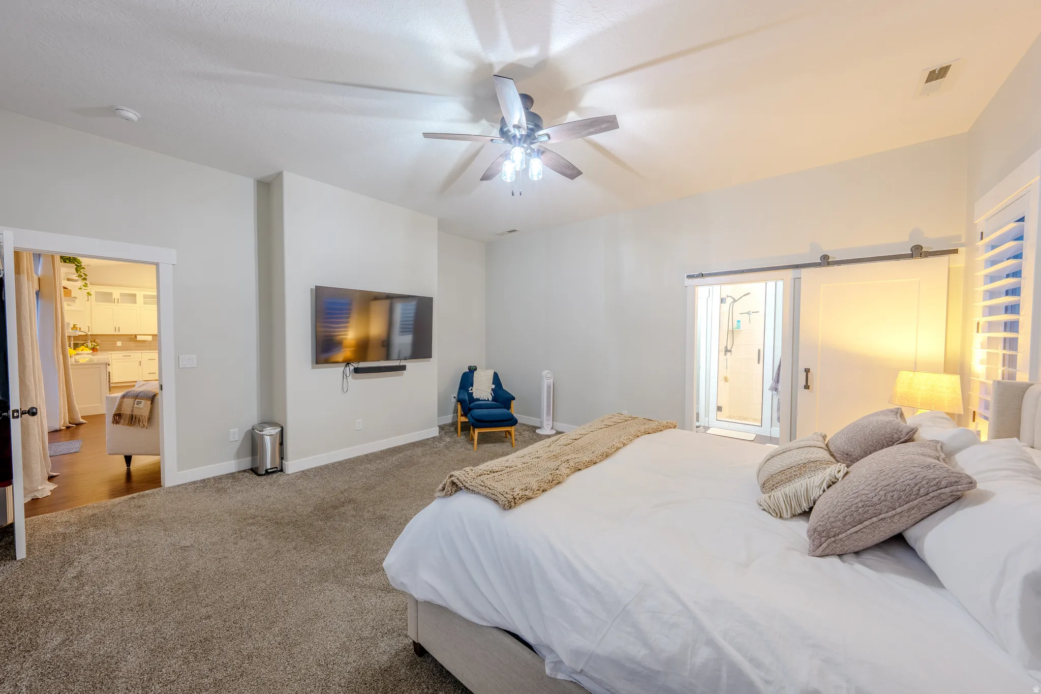Carpeted bedroom featuring a barn door and ceiling fan