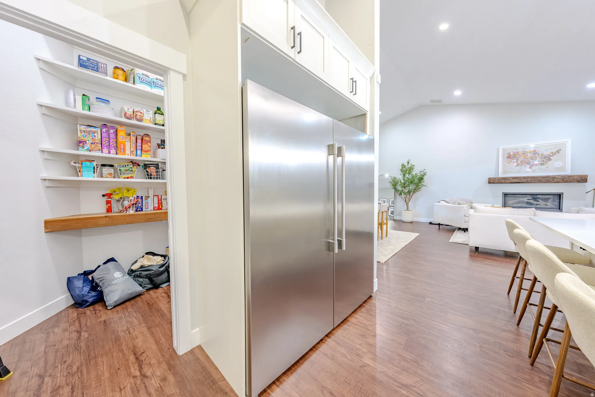 Kitchen with stainless steel built in refrigerator, light wood-type flooring, a glass covered fireplace, open floor plan, and recessed lighting