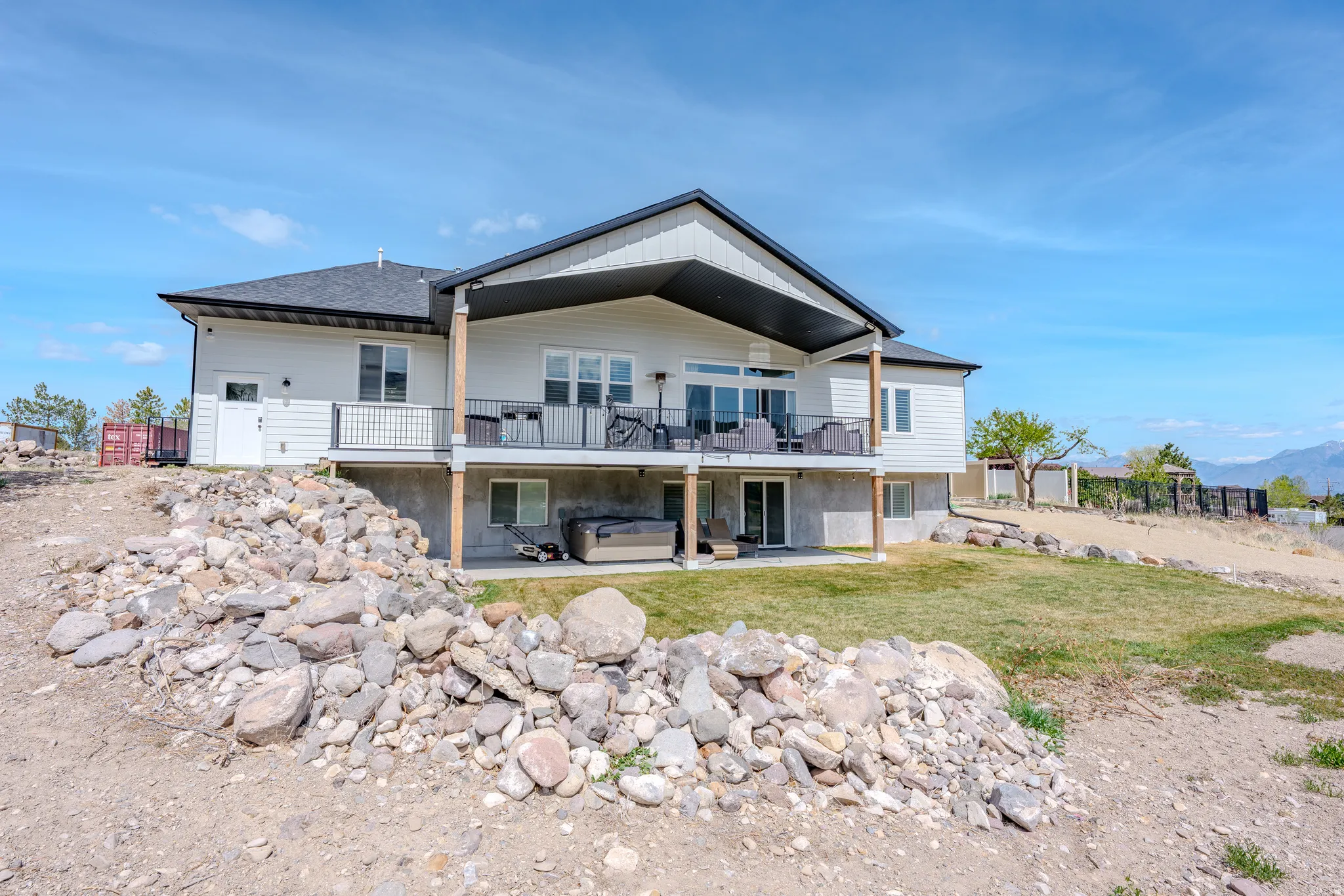 Back of property featuring a patio, a mountain view, a shingled roof, and a hot tub
