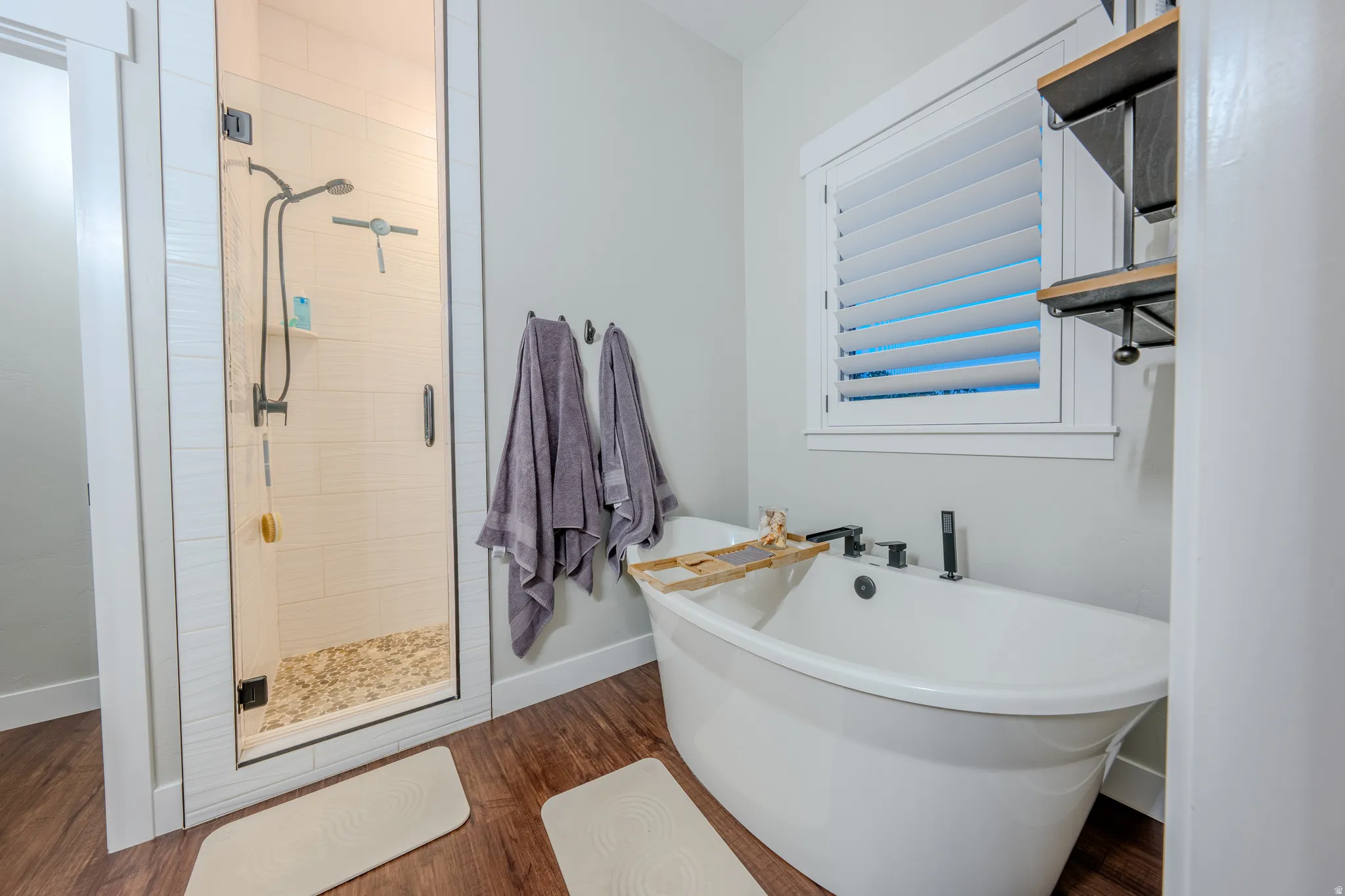 Full bathroom with a shower stall, a freestanding tub, and dark wood-style floors