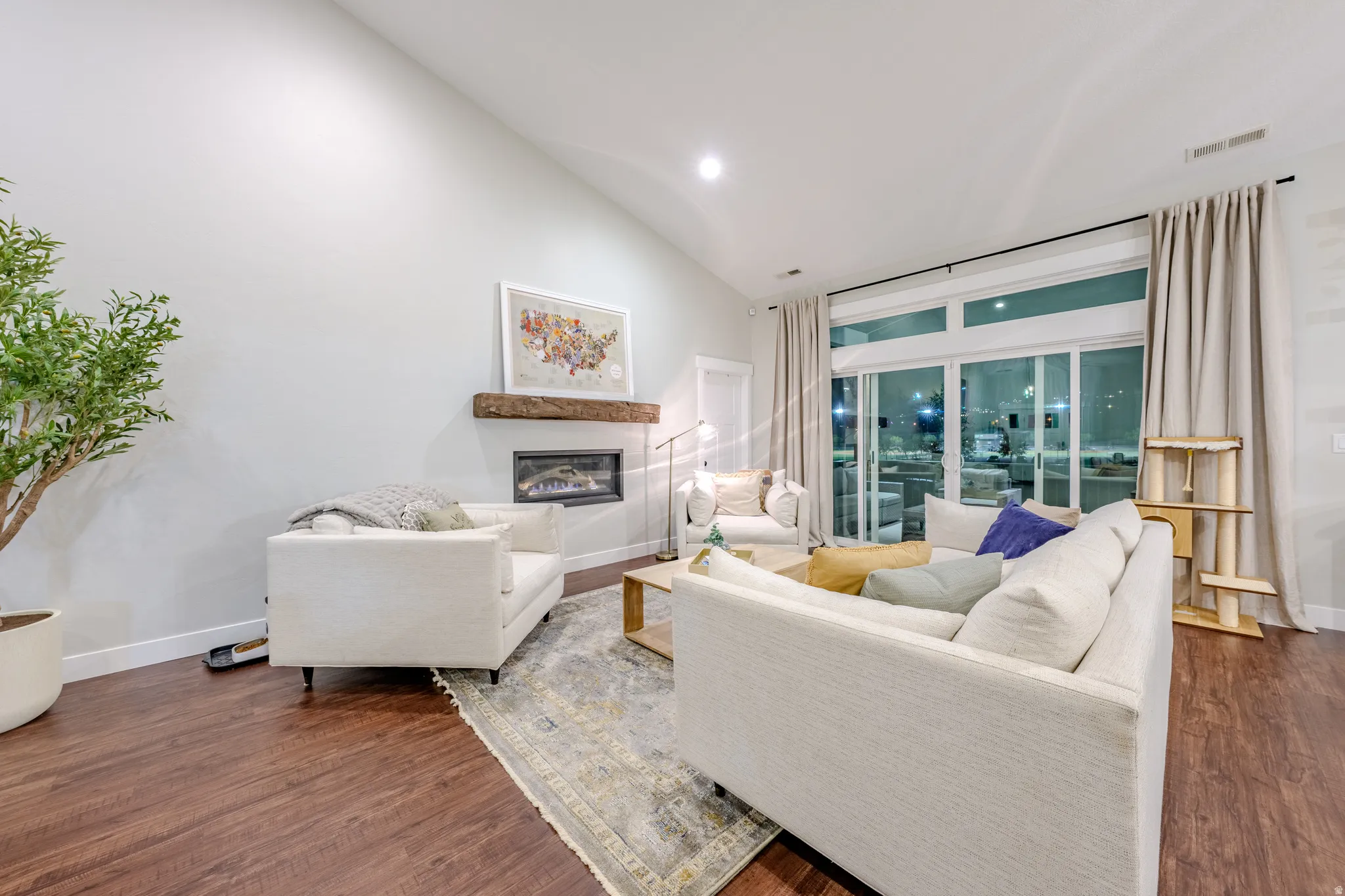 Living area with dark wood-style floors, lofted ceiling, a glass covered fireplace, and recessed lighting