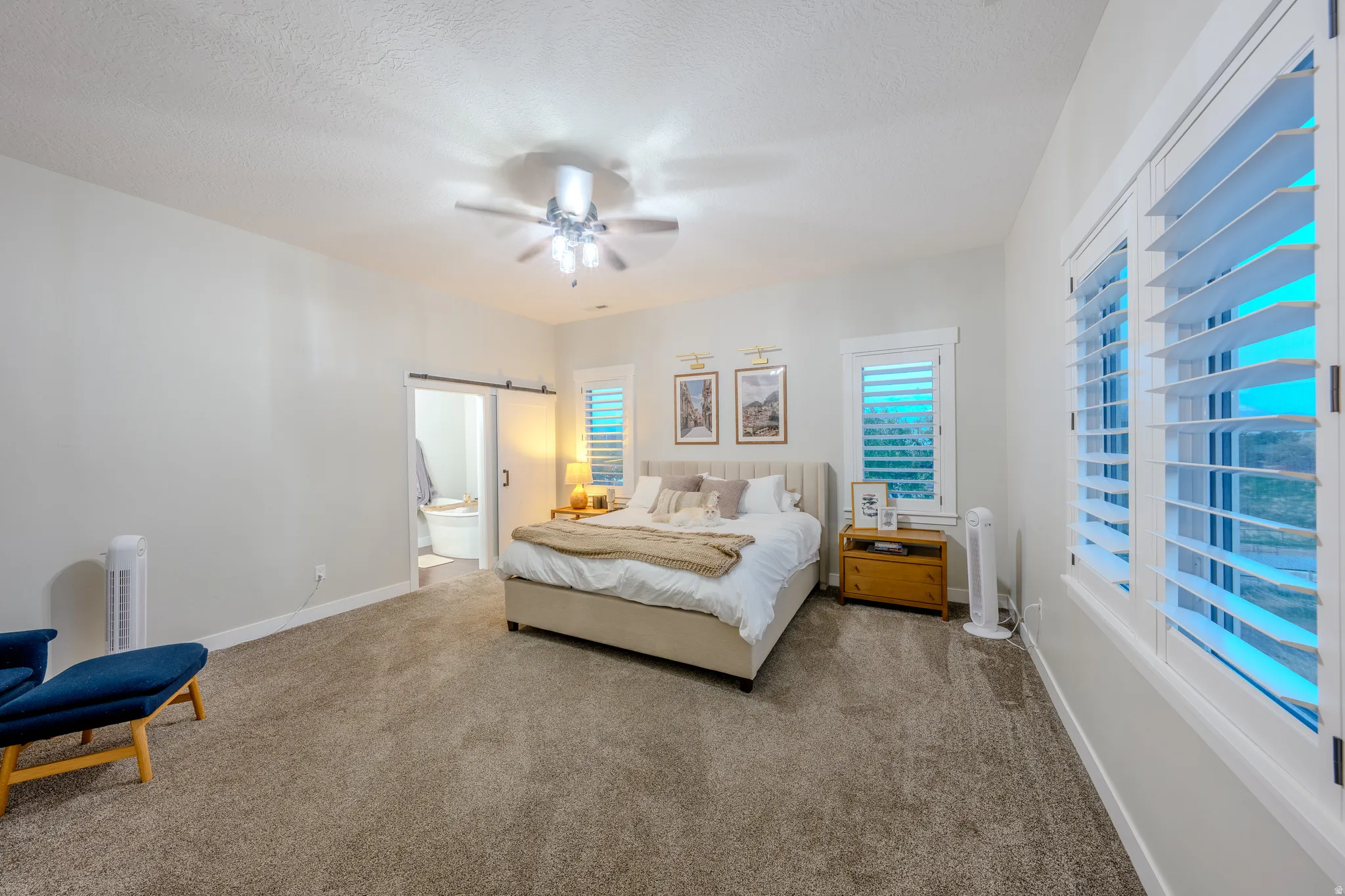 Carpeted bedroom with ceiling fan, a textured ceiling, and connected bathroom