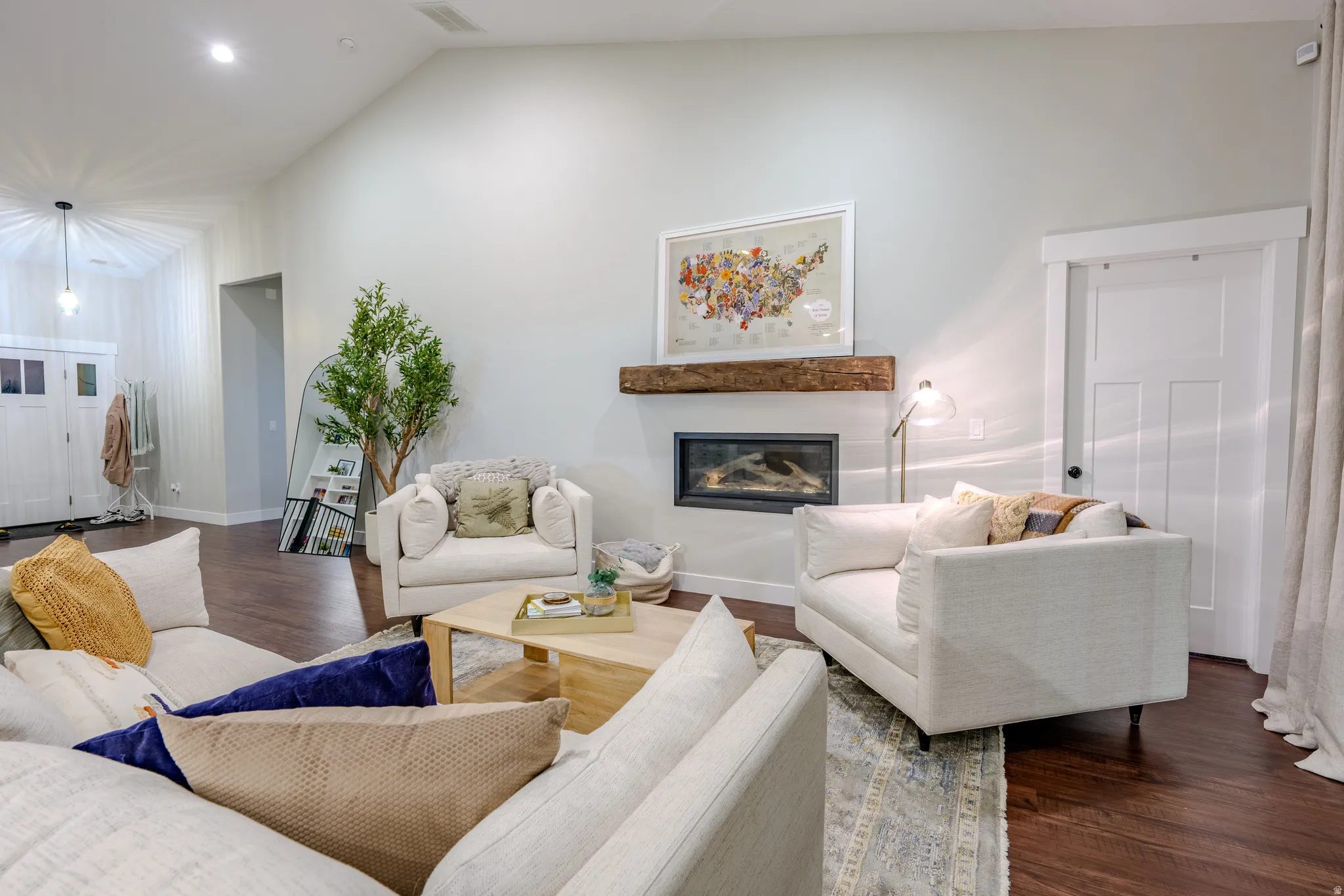 Living room featuring dark wood-style flooring, a glass covered fireplace, and lofted ceiling