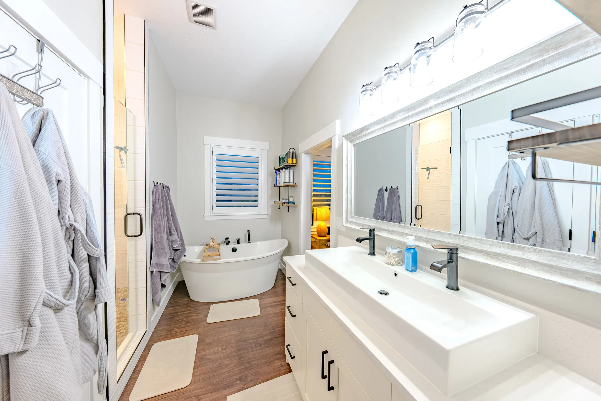 Full bathroom with vanity, a stall shower, a freestanding bath, and dark wood-type flooring