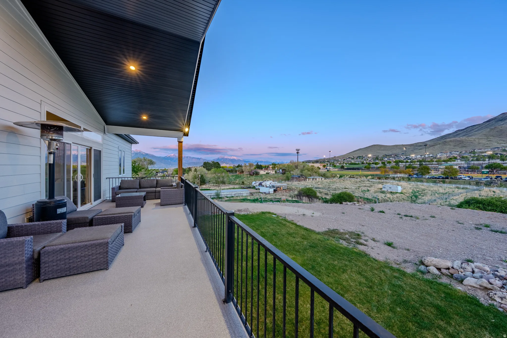 Patio terrace at dusk with outdoor furniture, a mountain view, and a yard