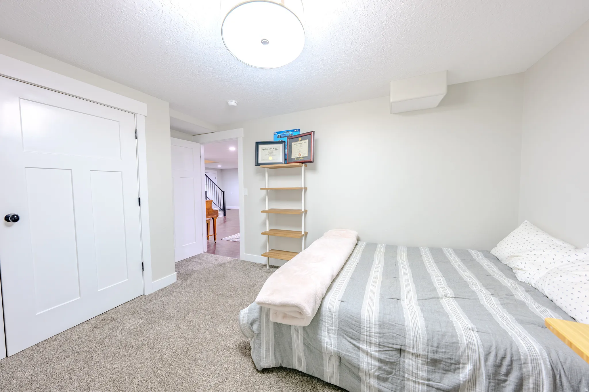 Bedroom with light colored carpet and a textured ceiling