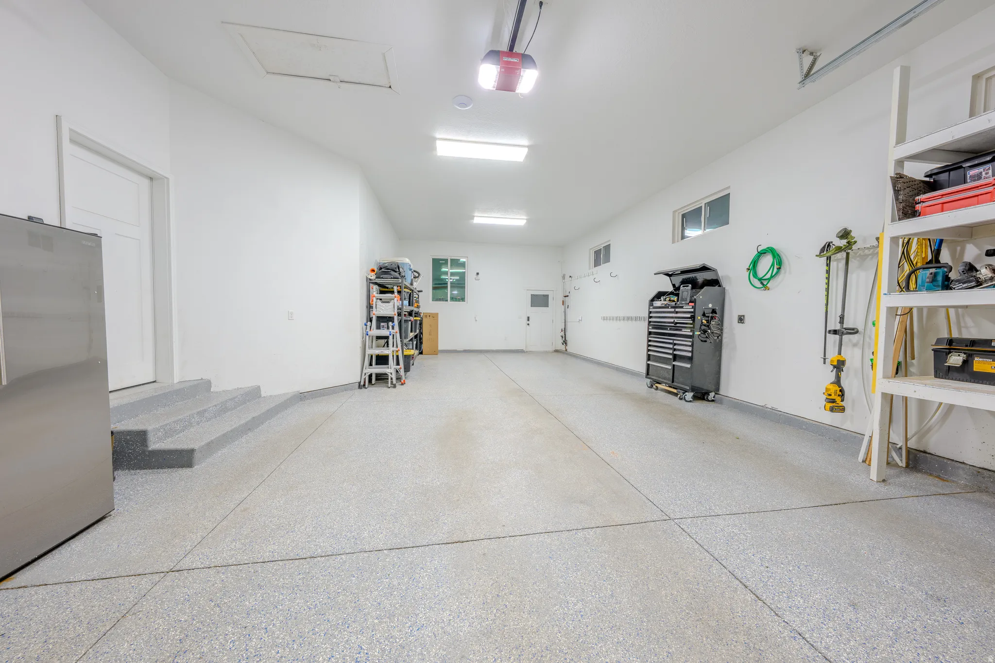 Garage with freestanding refrigerator and a garage door opener