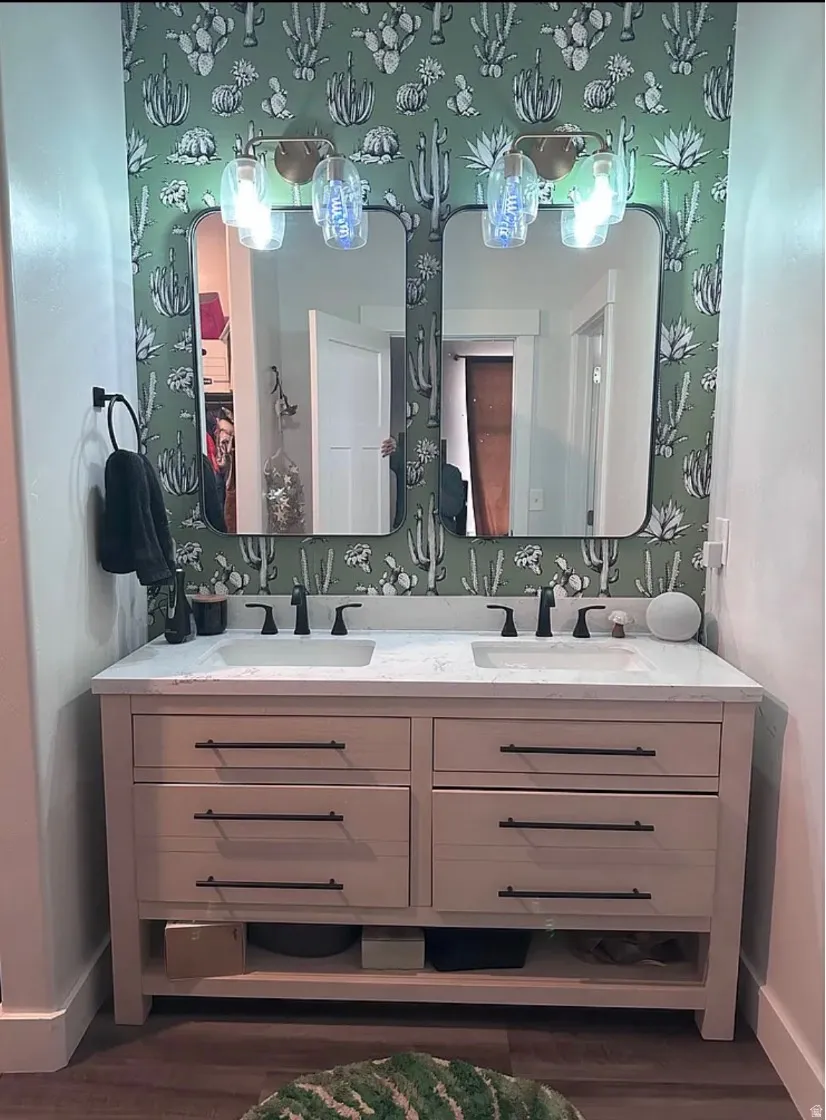 Full bath featuring double vanity and dark wood-style flooring