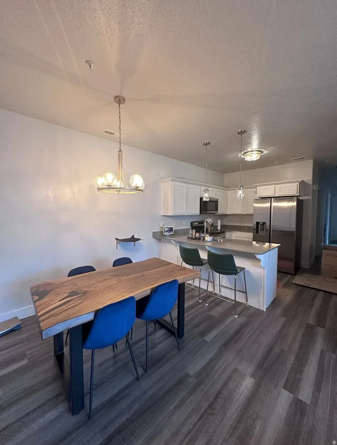 Dining area featuring dark wood-style floors, suspended lighting, and a textured ceiling