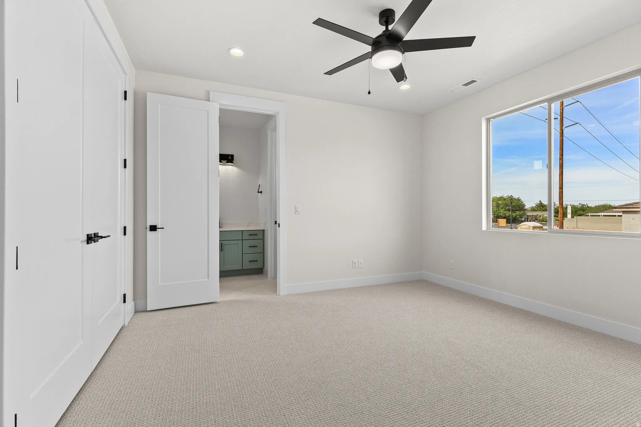 Unfurnished bedroom with light colored carpet, connected bathroom, ceiling fan, and recessed lighting