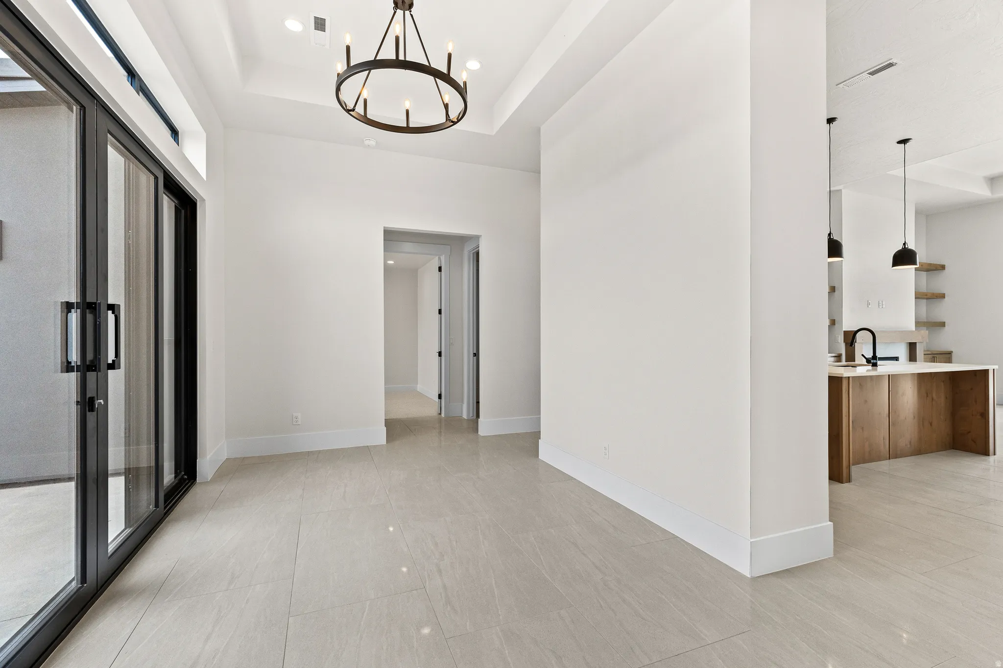 Corridor with hanging lights and a tray ceiling