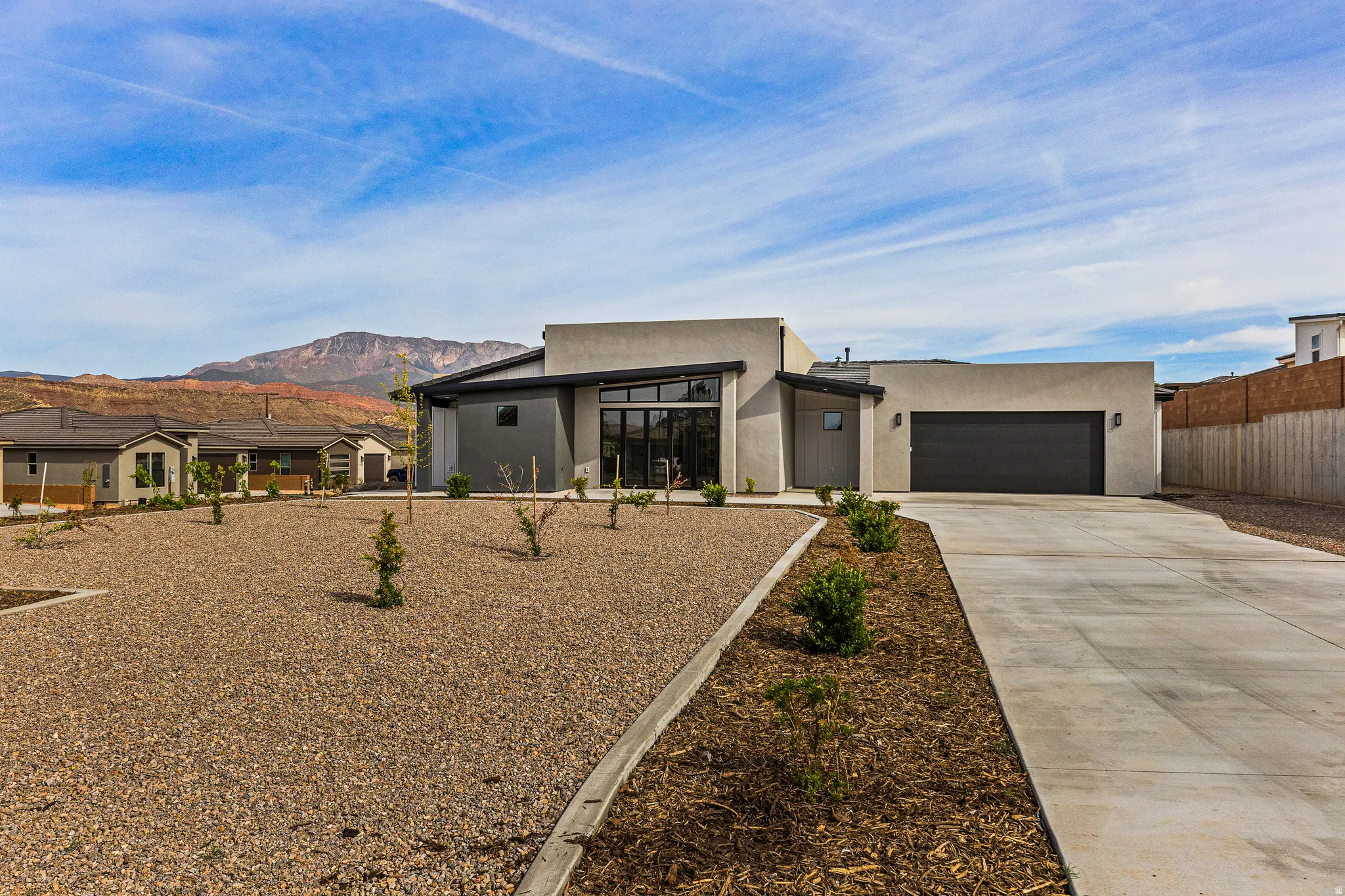 Contemporary house with a mountain view, driveway, stucco siding, and an attached garage