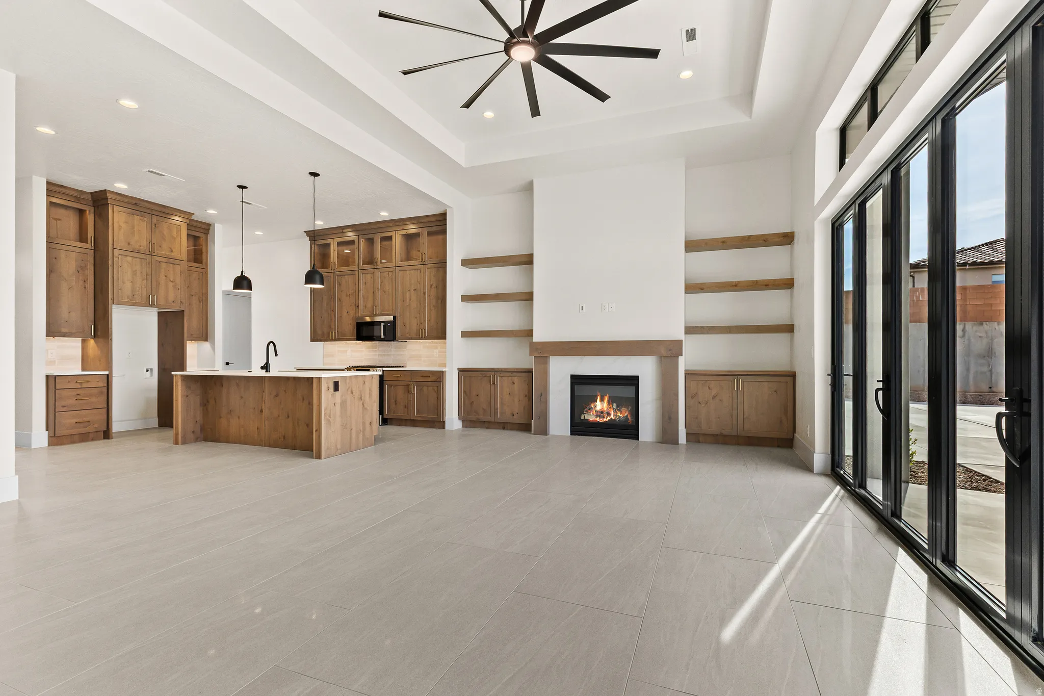 Kitchen with open floor plan, wood finish cabinetry, a kitchen island with sink, ceiling fan, and a raised ceiling