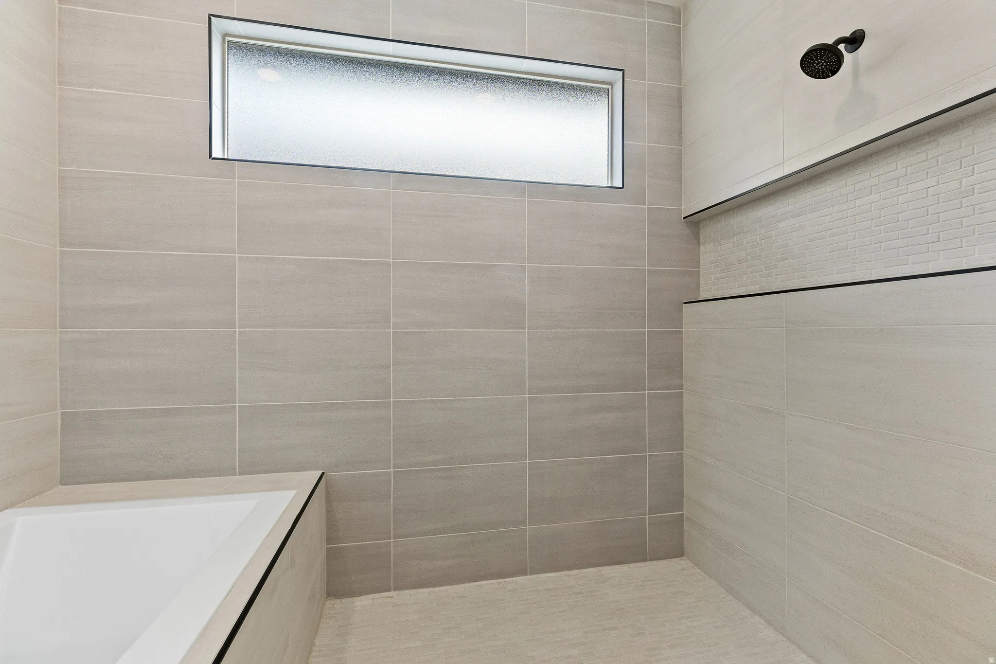 Bathroom featuring tiled shower and tile walls