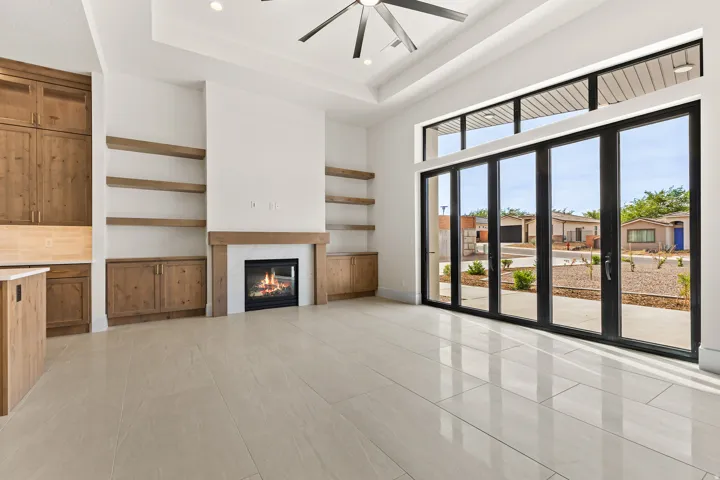Unfurnished living room featuring ceiling fan, a fireplace, recessed lighting, and a high tray ceiling