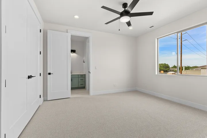 Unfurnished bedroom with light colored carpet, connected bathroom, ceiling fan, and recessed lighting
