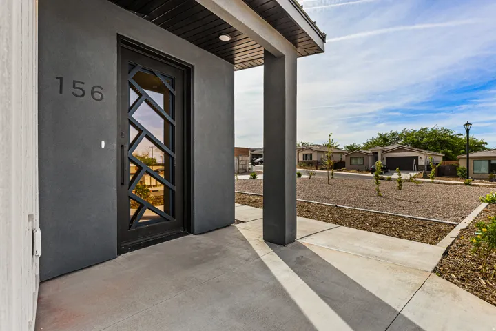 View of exterior entry with covered porch, stucco siding, and a residential view