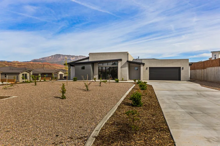 Contemporary house with a mountain view, driveway, stucco siding, and an attached garage