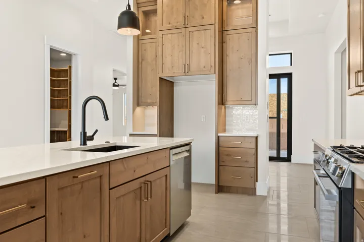 Kitchen with stainless steel appliances, pendant lighting, light stone counters, light tile patterned flooring, and tasteful backsplash