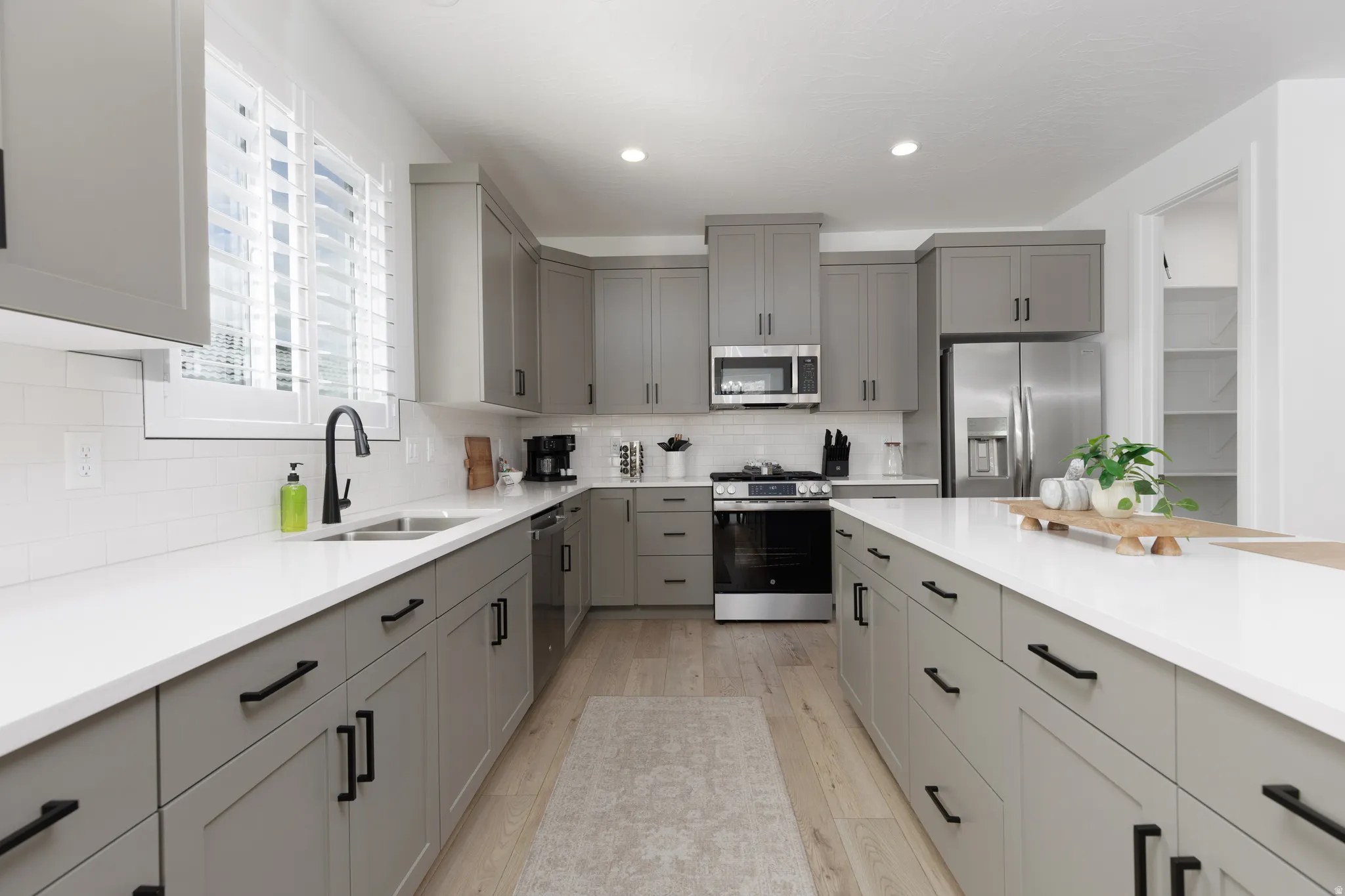 Kitchen with gray cabinets, stainless steel appliances, light wood-style floors, and recessed lighting