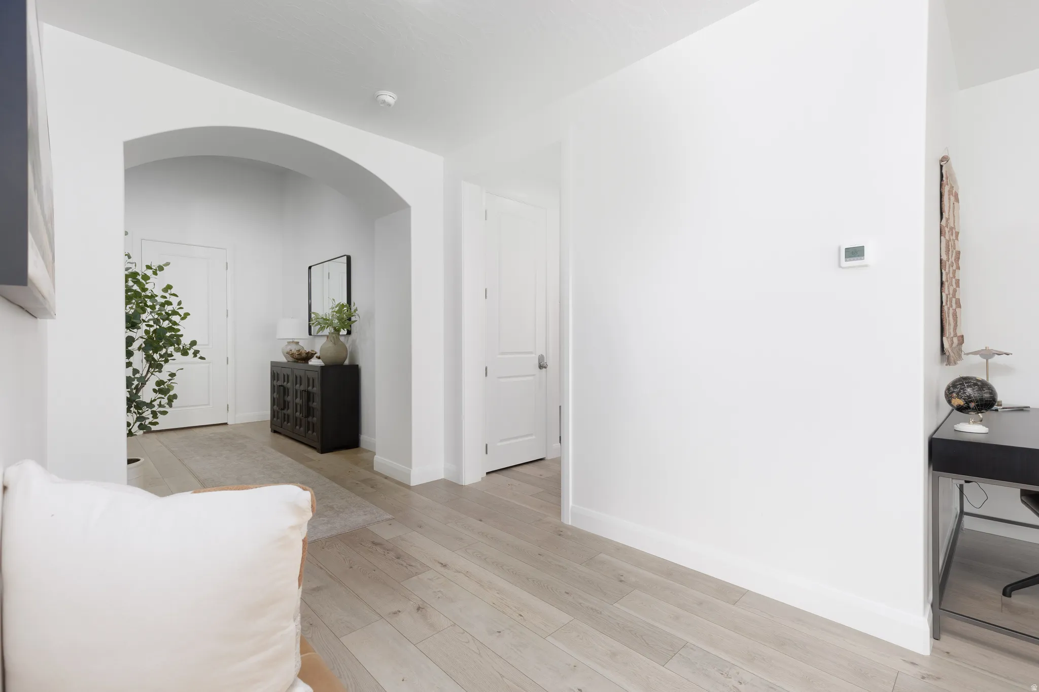 Hall featuring arched walkways and light wood-style floors