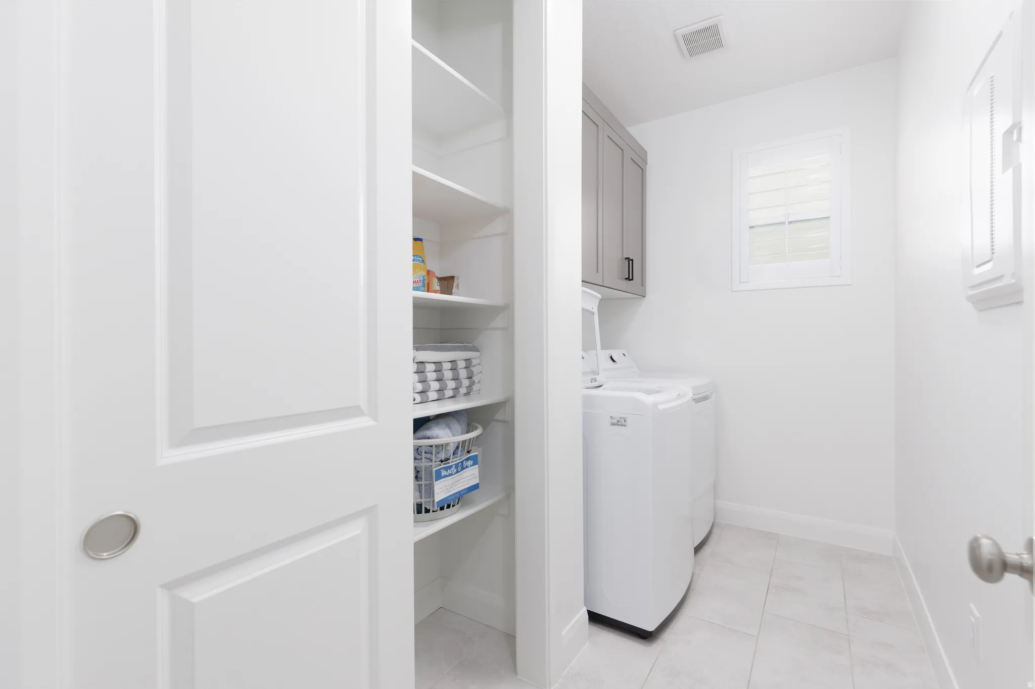 Laundry room with washer and clothes dryer, cabinet space, and light tile patterned floors