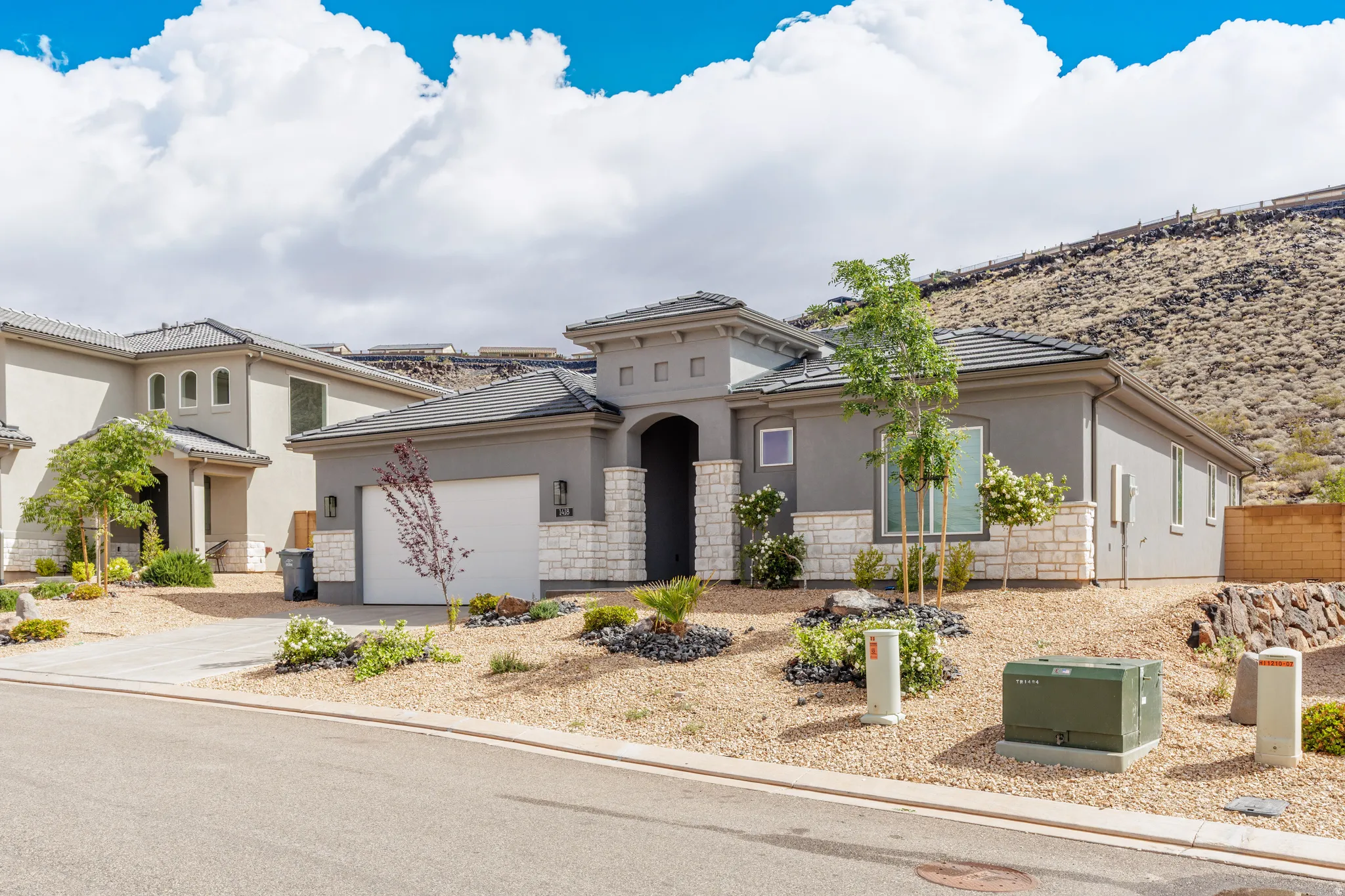 Mediterranean / spanish house with stucco siding, stone siding, concrete driveway, and an attached garage