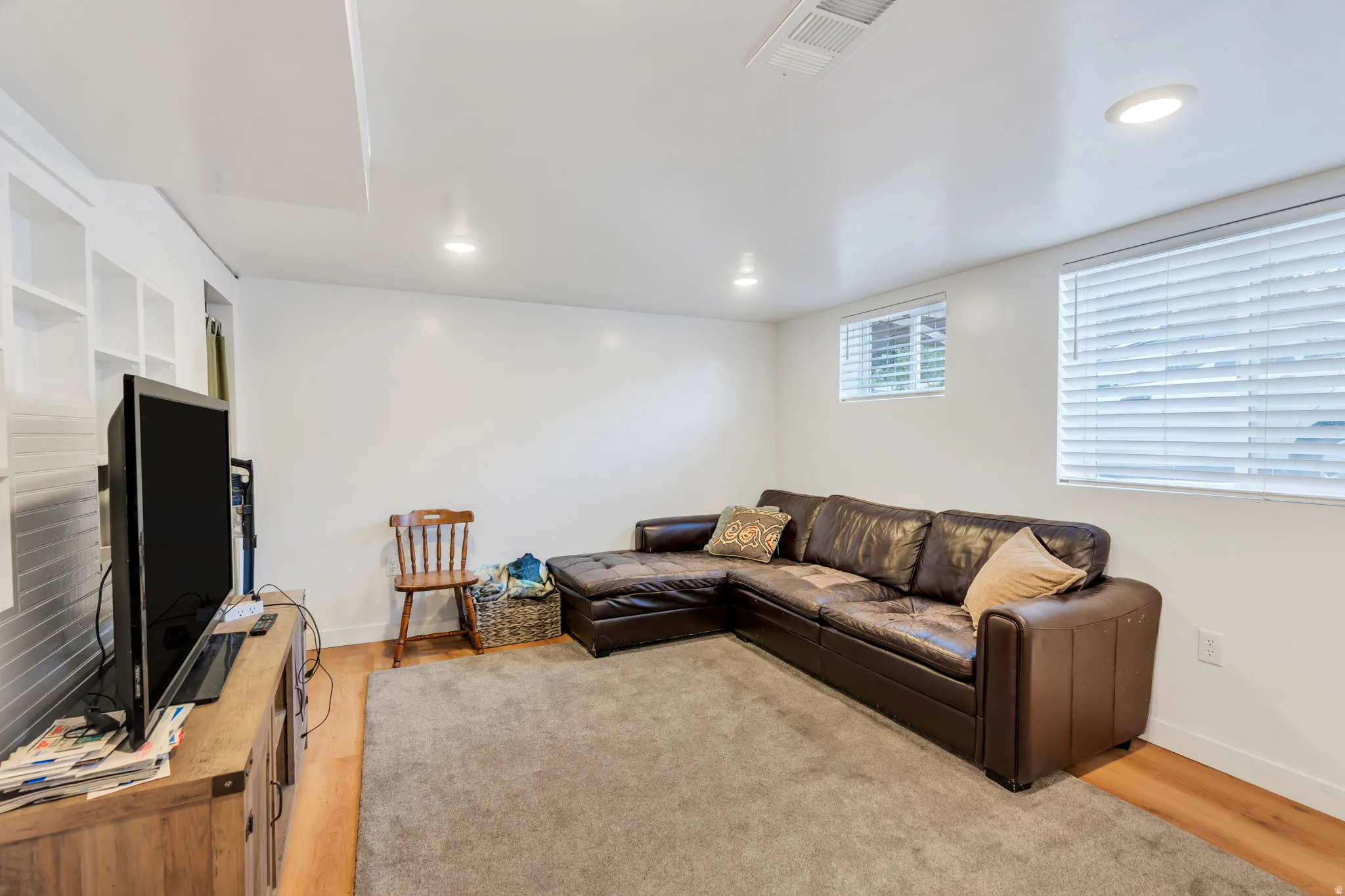Living room with light wood-style flooring and recessed lighting