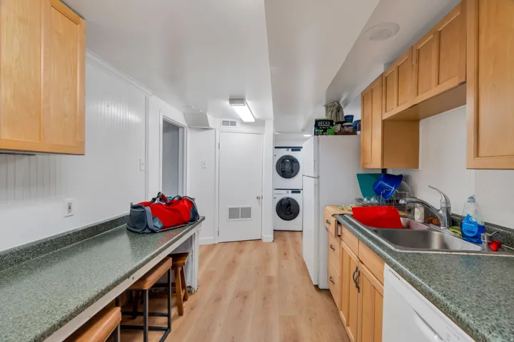 Kitchen with dark countertops, white appliances, light wood-style floors, and light wood finish cabinetry