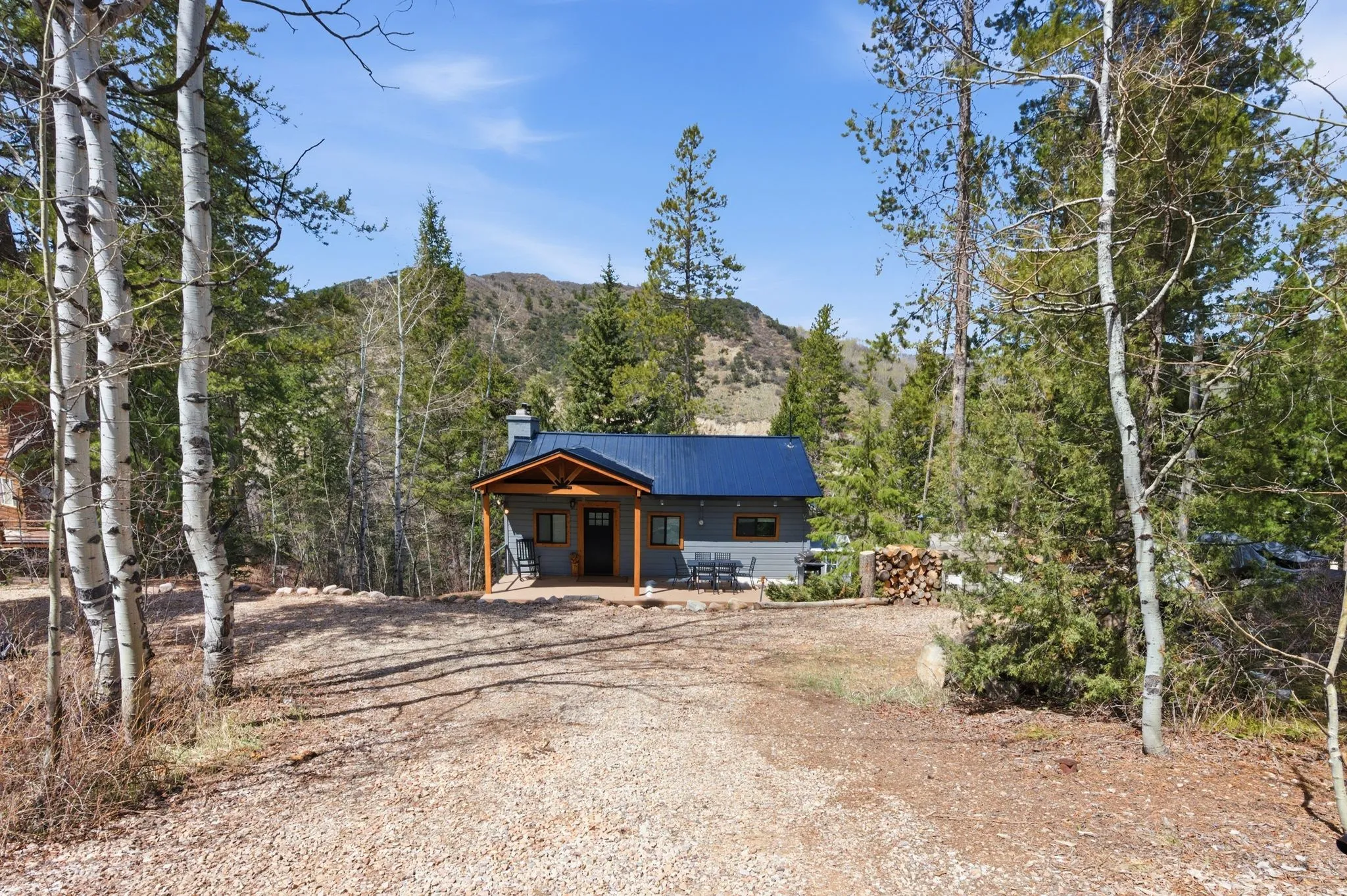 View of front of home with a patio area, a mountain view, a metal roof, graveled horseshoe shaped driveway, and a chimney